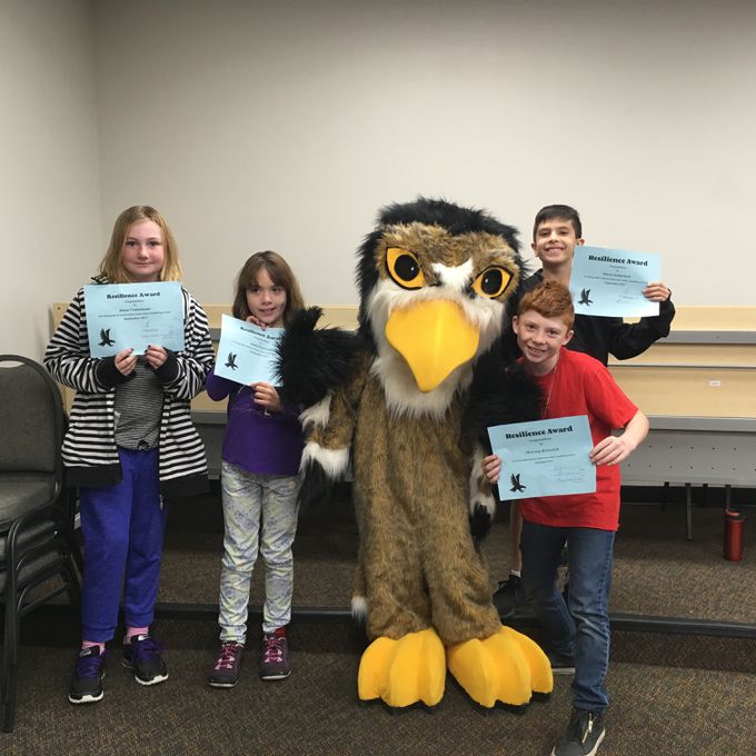 Group of students with awards surround mascot of Falcon named Echo
